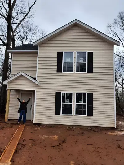 Completed two-story home exterior with new siding and a person standing at the front entry
